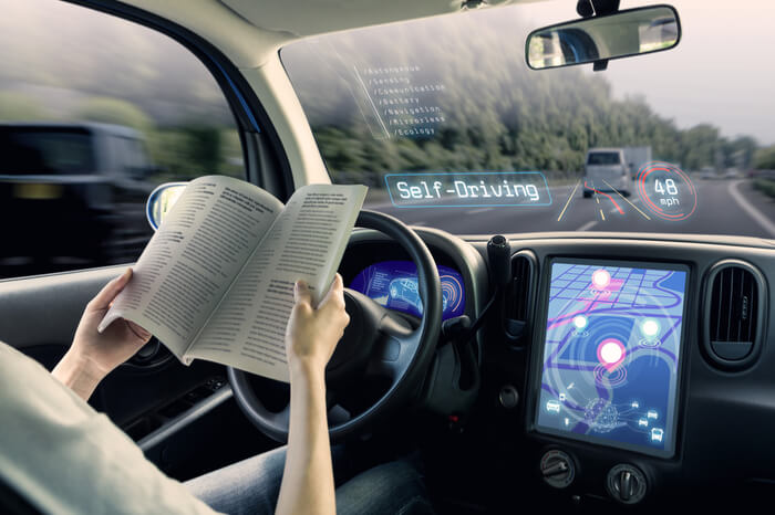 Autonom fahrendes Auto, Fahrer liest eine Zeitung 