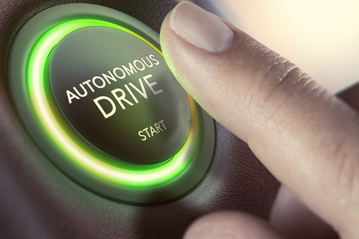 Finger drückt auf Start-Button für autonomes Fahren