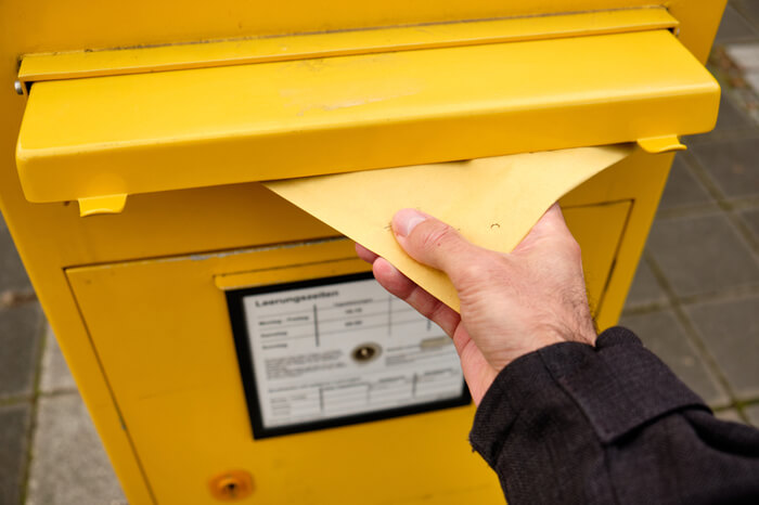 Person wirft Brief in Briefkasten