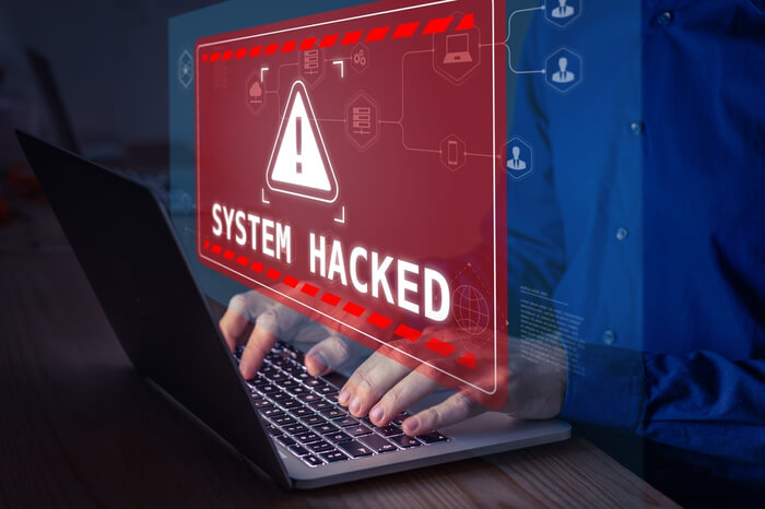 Person am Laptop hackt sich in ein System Warnmeldung