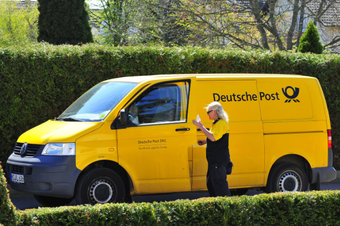 Zustellerin mit Lieferfahrzeug der Deutschen Post