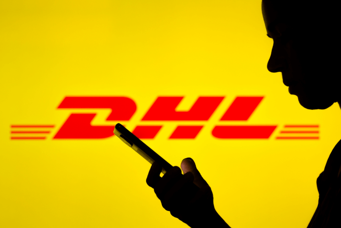 App: Handy-Nutzer vor einem DHL-Logo